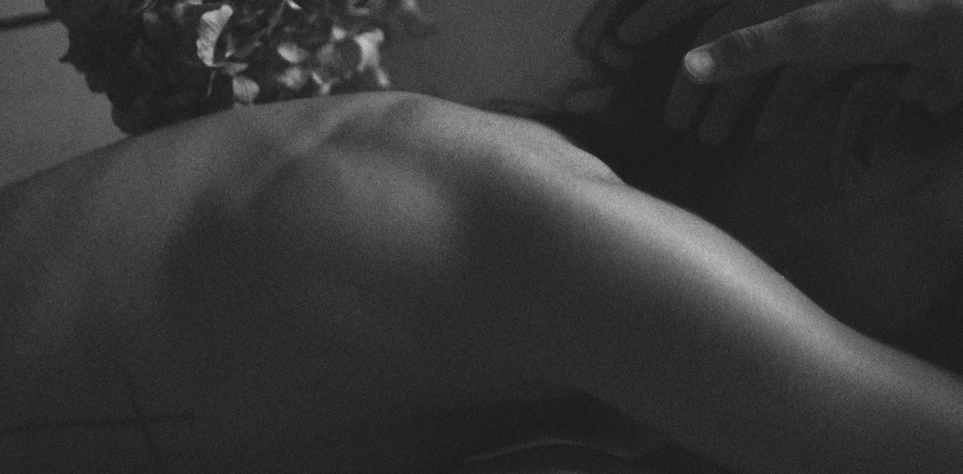 Close-up of a person's back with a blurred flower arrangement in the foreground