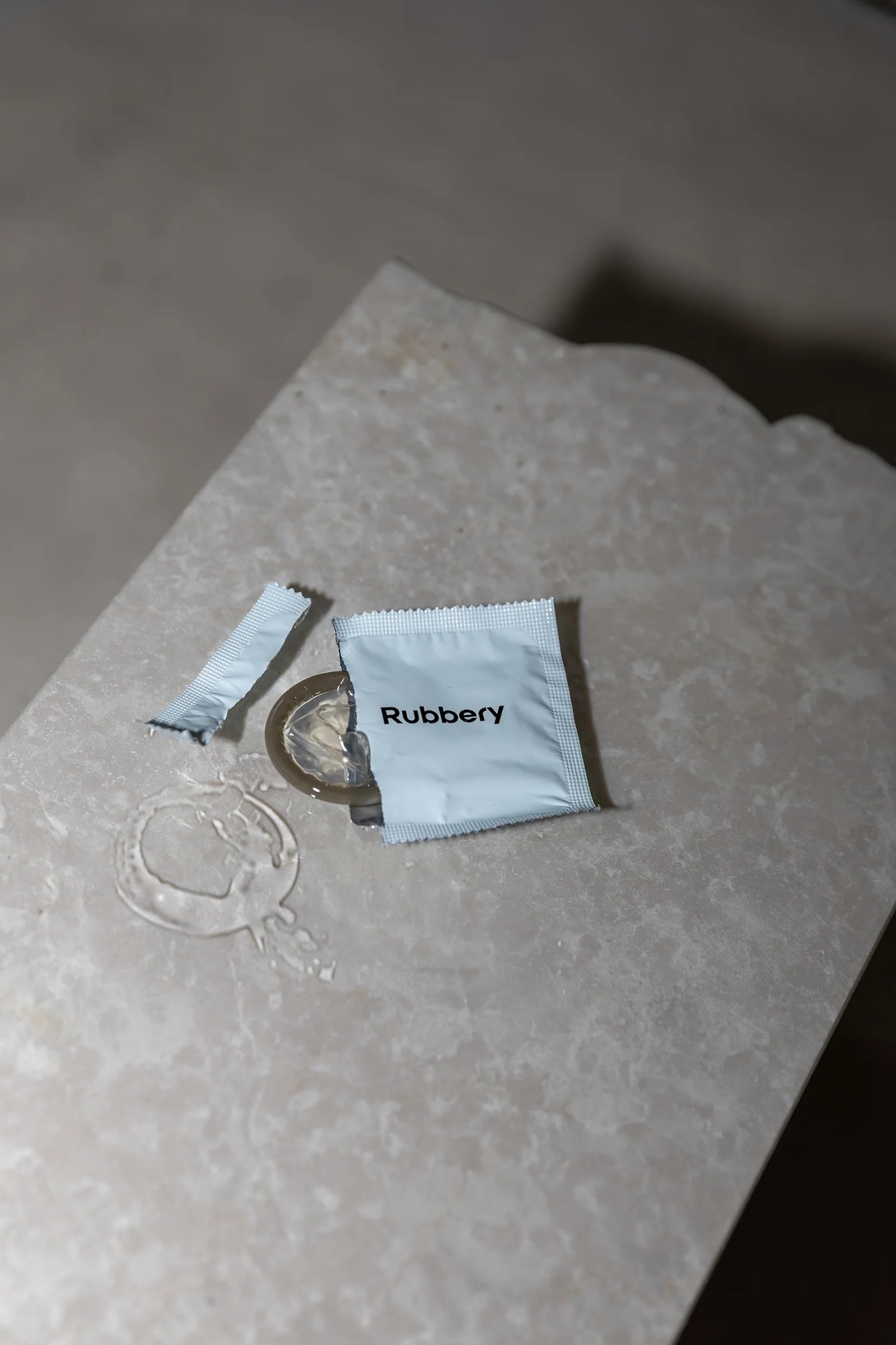 Close-up of a Rubbery condom and wrapper on a textured stone surface