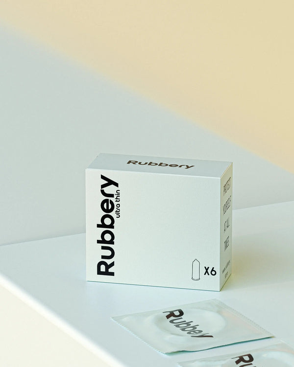 Rubbery ultra thin condom box with individual packets on a light pastel surface