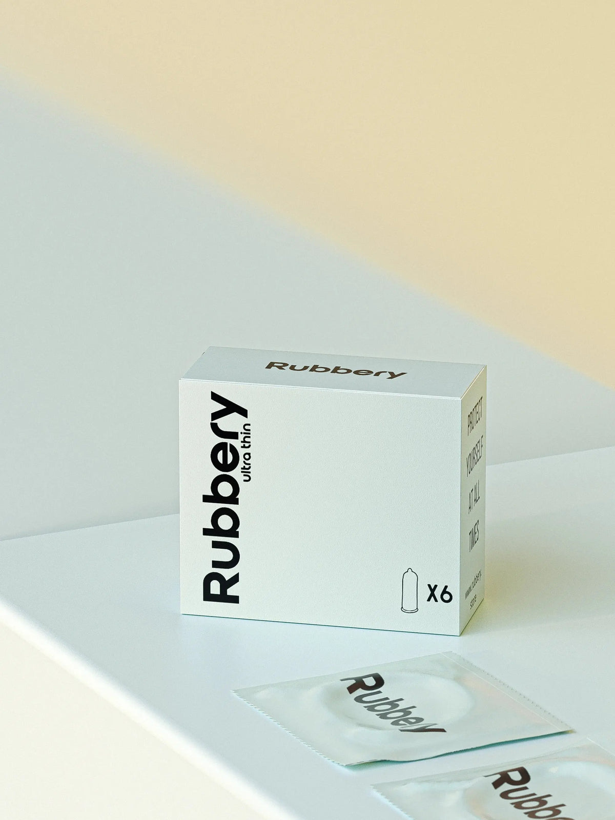 Rubbery ultra thin condom box with individual packets on a light pastel surface