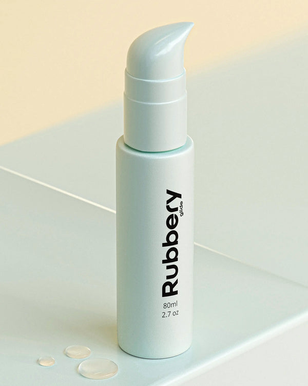 Rubbery intimate lubricant bottle on a light surface with water droplets